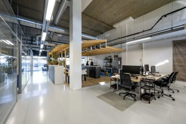 Modern kantoorinterieur aan de Joan Muyskenweg met open werkplekken, industriële details en een centraal gelegen pantry.